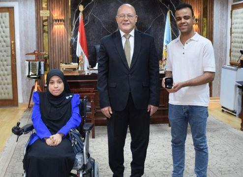 جامعة سوهاج تهدي طالبة وطالب من ذوي الهمم كرسي متحرك كهربائي وسماعتي أذن