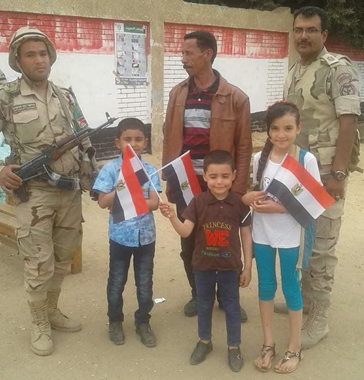   الأطفال يرفعون علم مصر أمام لجنة انتخابية ببني سويف